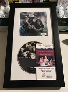 CD FIRMADO EN CUERO CODY JOHNSON AUTOGRAFIADO ENMARCADO Y MATE CERTIFICADO DE AUTENTICIDAD JSA AY98987 RARO - Imagen 1 de 5
