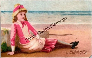 Antike viktorianische Neujahrskarte Mädchen im rosa Kleid entspannend am Meer - Bild 1 von 2