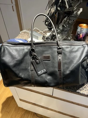 Bolsa de viaje de fin de semana TUMI 21x9 CUERO NEGRO con correa para el hombro y etiqueta de equipaje con bloqueo Foto 1 de 4