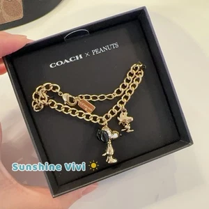 Bracciale Charm Coach x PEANUTS Snoopy e Woodstock CCA50 Oro/Nero Nuovo con etichette - Foto 1 di 6