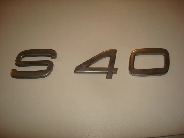 2000 VOLVO S40 ЗАДНЯЯ КРЫШКА БАГАЖНИКА ДЕКА ХРОМИРОВАННАЯ ЭМБЛЕМА ЛОГОТИП ЗНАЧОК НАКЛЕЙКА БУКВЫ OEM - Изображение 1 из 1