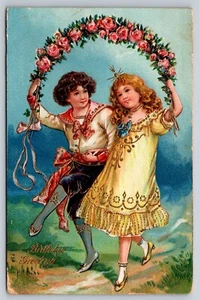 Postal Felicitación Cumpleaños, Niño y Niña Bajo Corona Rosa Alemania c 1909 20z - Imagen 1 de 2
