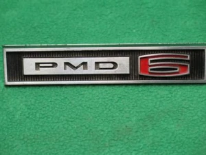 9780110 GM 1965 PONTIAC TEMPEST PMD-6 GUARDABARROS DELANTERO EMBLEMA ADORNO 6 CILINDROS NOS - Imagen 1 de 1