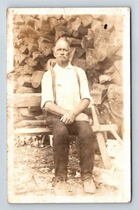 Old Man Sitting On Bench In Front Of Large Wood Pile Real Photo Postcard RPPC - Picture 1 of 2