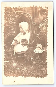 Kind & Puppe sitzt im Korb Echt Foto Postkarte RPPC C405 - Bild 1 von 2