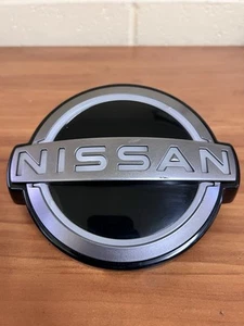 2023-2024 NISSAN ARIYA GRILLE EMBLEM EMPOWER 62890-5MP0B. OEM - Picture 1 of 3