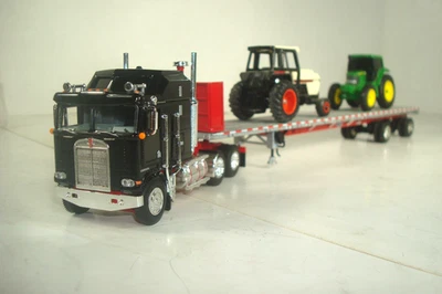 Camión cama Kenworth K100 DCP y remolque de plataforma plana Roadbrute y 2 tractores JD 1:64 Foto 1 de 4