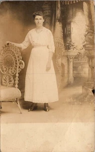 Early 1900's RPPC Beautiful Woman In White Dress Standing by Ornate Chair - Picture 1 of 3