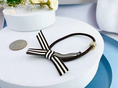 Henri Bendel Tono Dorado Cristales Icónicos y Lazo Logo Corbata Cola de Caballo Soporte Foto 1 de 4