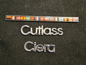 VINTAGE 3 PC OLDSMOBILE- CUTLASS CIERA INTERNATIONAL FLAG FENDER EMBLEM- OEM GM - Bild 1 von 6