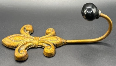 Antiguo gancho de pared de hierro fundido dorado Fleur De Lis con perilla de vidrio negro Foto 1 de 4