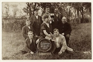 EIGHT MEN IN THE GERMAN COUNTRYSIDE DRINKING BEER; ONE IS WEARING A DRESS (1927 - Picture 1 of 5