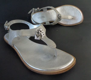 Sandalias planas MICHAEL KORS US 6,5 M Suki plateadas metálicas tanga correa en T con dijes - Imagen 1 de 9