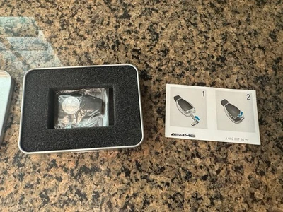 Genuine OEM Mercedes Benz Silver AMG Logo Key Cover Part: A0008900023 - Image 1 of 4