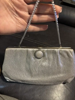 Bolso de mano de noche de tela metalizada plateada con correa de cadena y cierre decorativo Foto 1 de 3