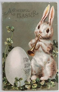 Conejito de Pascua antropomórfico tocando cuerno a huevo gigante y tréboles, en relieve Nuevo de Lote Antiguo - Imagen 1 de 3
