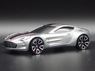 Modello Auto Diecast Diorama In Scala 1/64 Aston Martin One-77 Argento 2009-2012 - Immagine 1 di 4