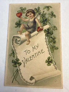 Geprägte Valentinstag Postkarte Amor Cherub sitzend auf Schild Deutschland - Bild 1 von 2