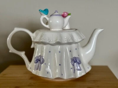Tetera blanca Teleflora vintage con lazos morados, pájaro azul y tapa de flor rosa Foto 1 de 3