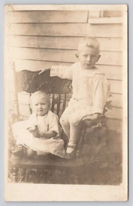 RPPC de niño y niña sentados en silla de madera AZO c1918-1930 foto postal - Imagen 1 de 2