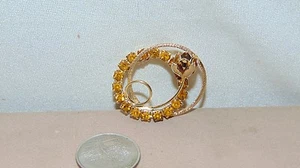 BROCHE REDONDO EN TONO DORADO CON PIEDRAS ROSAS Y NARANJAS - Imagen 1 de 6
