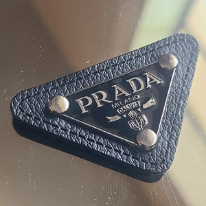Placa triangular The Emblem (una pieza) Prada negra con logotipo plateado repuesto - Imagen 1 de 1