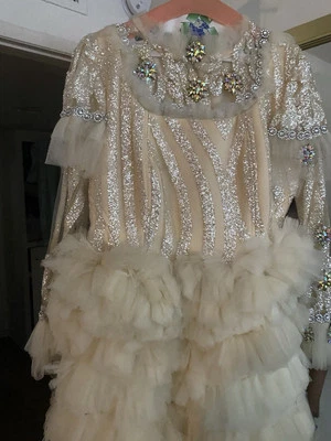 Vestido corto beige hecho en Nigeria y tiene mangas con piedras preciosas grandes  Foto 1 de 2