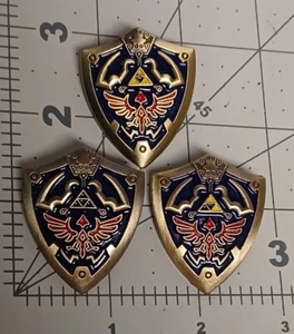 Spilla smaltata The Legend of Zelda Hylian Shield, varianti danneggiate, lotto di 3 - Foto 1 di 2