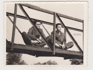 Due giovani uomini seduti a gambe incrociate sul ponte vicinanza poetica snapshot gay int - Foto 1 di 8