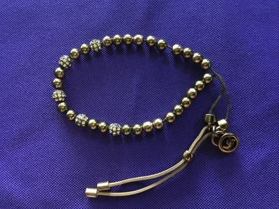 PULSERA DESLIZANTE ELÁSTICA CON CUENTAS TONO DORADO FIRMADA POR EL DISEÑADOR MICHAEL KORS Foto 1 de 4