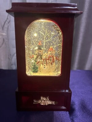 Globo de nieve de recuerdo navideño de luz y movimiento nostálgico con familia muñeco de nieve Foto 1 de 4