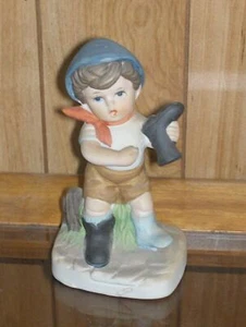 Boy Sitting on a Fence with One Boot in His Hand - Picture 1 of 1