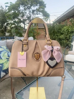 Cartera con lazo beige Juicy Couture con dije de espejo de corazón y herrajes dorados Foto 1 de 4