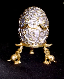 Delicioso huevo de lavanda y esmalte dorado sobre soporte de latón con elefantes - Imagen 1 de 3
