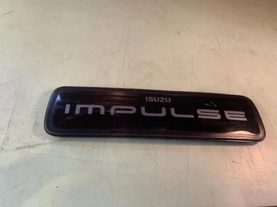 83-87 OEM Isuzu Impulse panel de ajuste trasero adorno luz trasera emblema insignia logotipo Foto 1 de 4