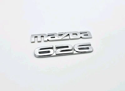 1999-2002 MAZDA 626 TAMPA DO PORTÃO TRASEIRO EMBLEMA LOGOTIPO EMBLEMA SINAL SÍMBOLO CONJUNTO FABRICANTE DE EQUIPAMENTO ORIGINAL - Imagem 1 de 3
