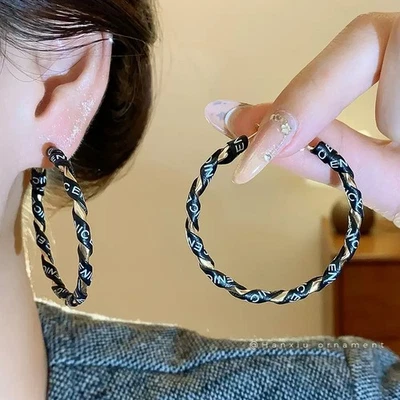 Pendientes de aguja de plata con letra circular geométrica envuelta en cuero retro para mujer Foto 1 de 4