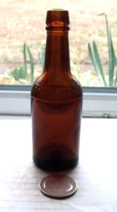 SAMPLE BROWN FANCY LIQUOR BOTTLE EMBOSSED, P F HERING, BASE HAS A WAGON WHEEL - Picture 1 of 1