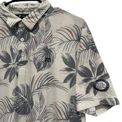 Camisa polo de golf Travis Mathew para hombre con estampado de hojas tropicales "The Hills" Country Club Foto 1 de 4